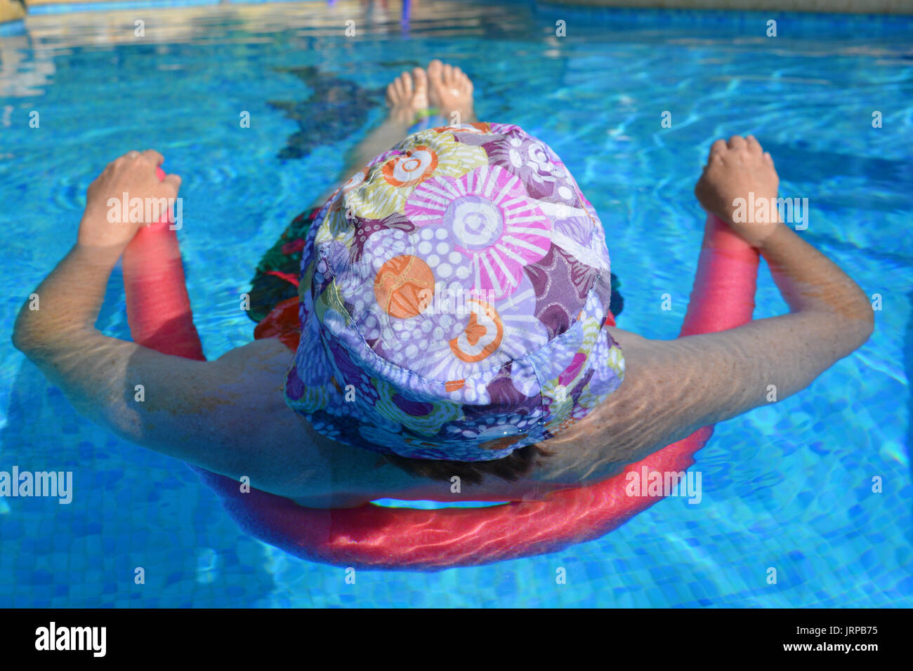 Estate vibes! Donna flottante in una piscina con un pool noodle. Foto Stock