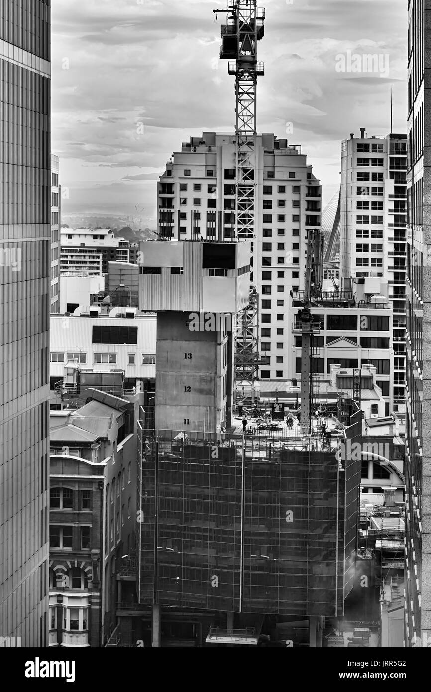 Sito in costruzione del grattacielo di salita edificio nella città di Sydney CBD. Commercianti dei lavoratori durante il lavoro con macchinari da costruzione, il sollevamento di carichi pesanti e gru Foto Stock