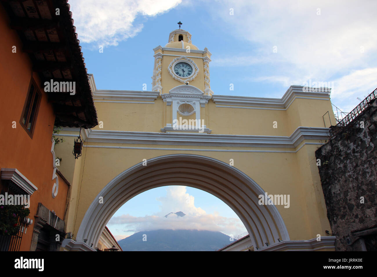 Arco con reloj en la calle principal de La Antigua Guatemala, al fondo se ve el volcán de agua, el arco es icono de la ciudad y onu punto de encuentro Foto Stock