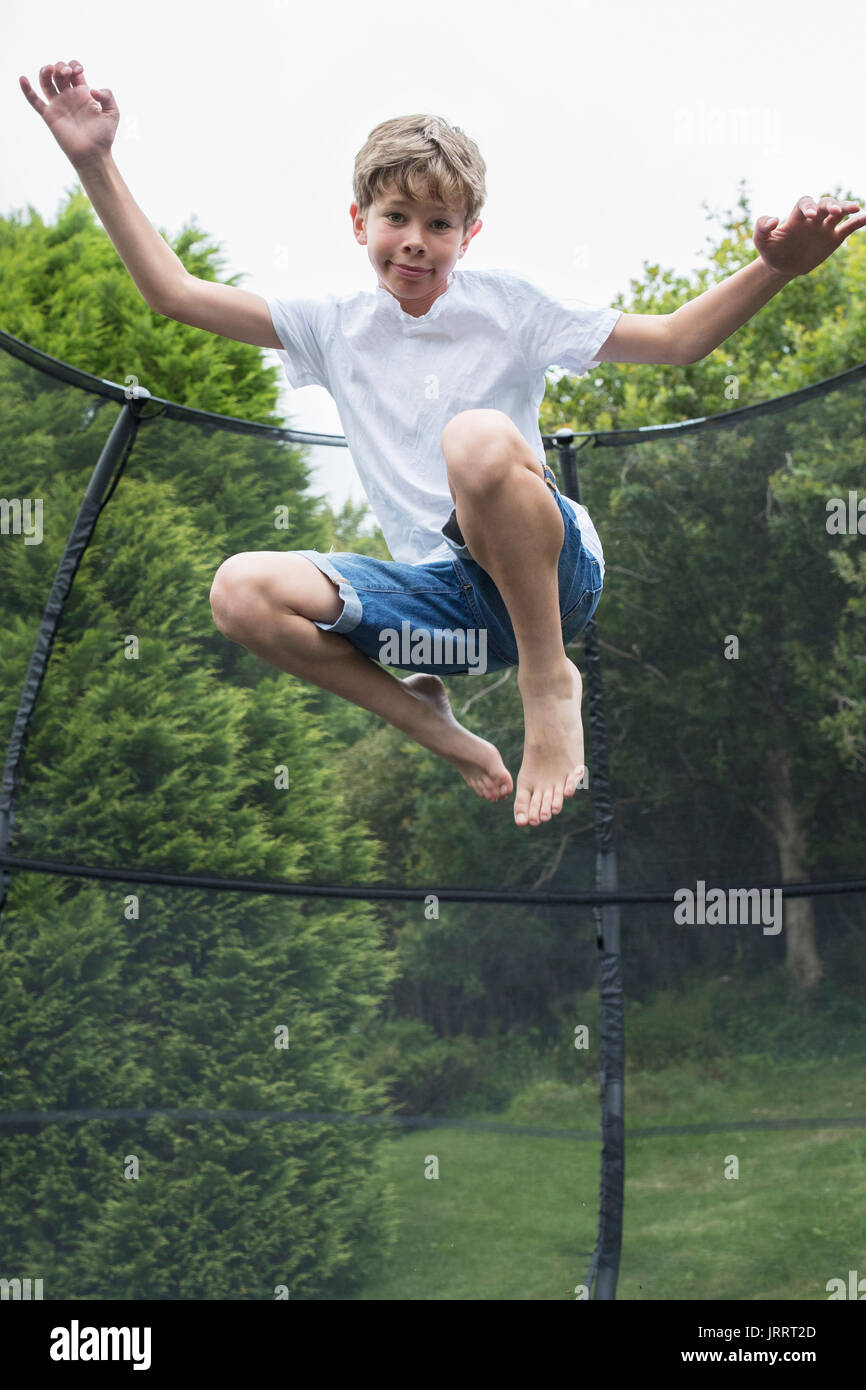 Mid Air Shot del ragazzo sul trampolino in giardino Foto Stock