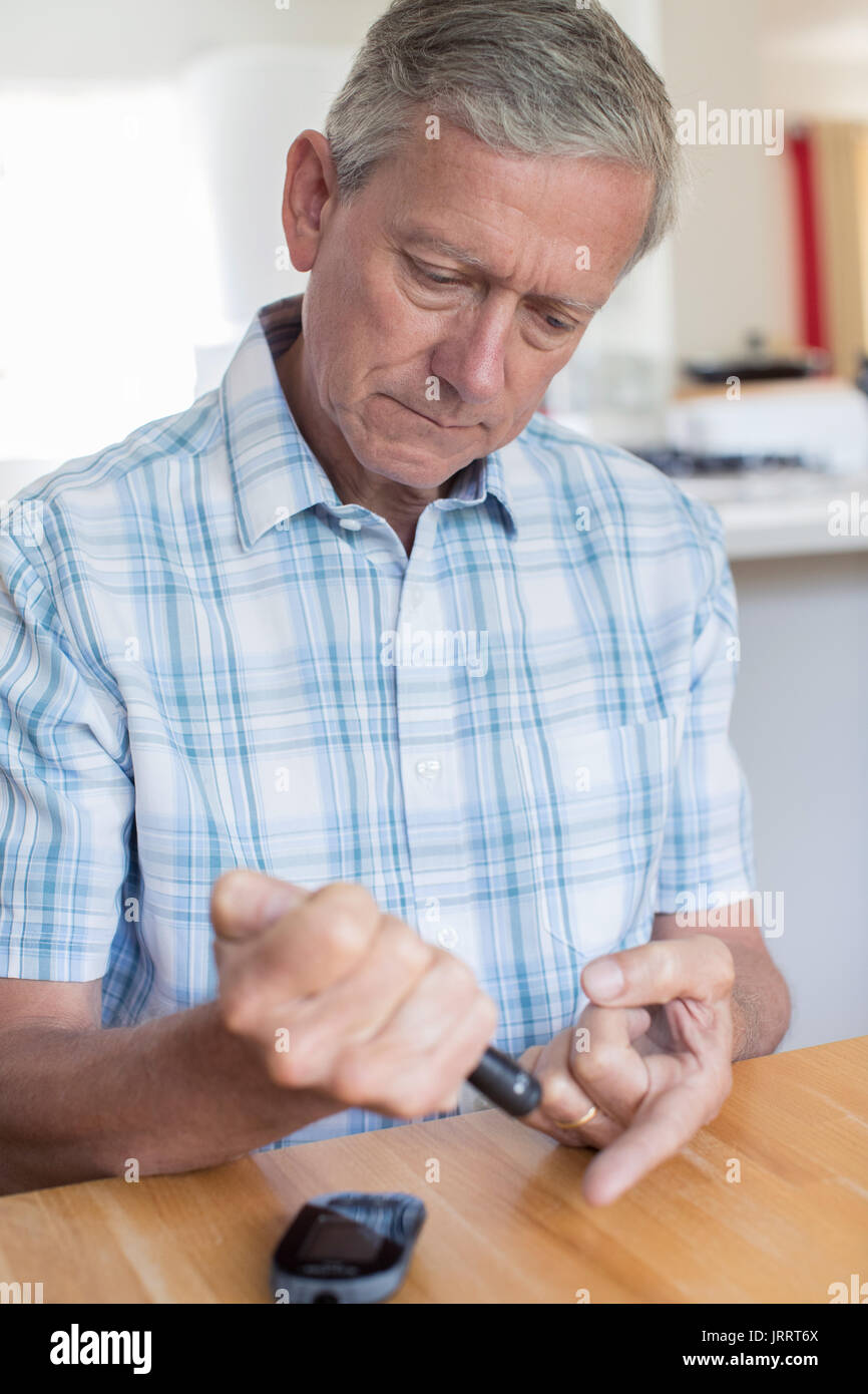 Uomo maturo test livello di zucchero nel sangue a casa Foto Stock