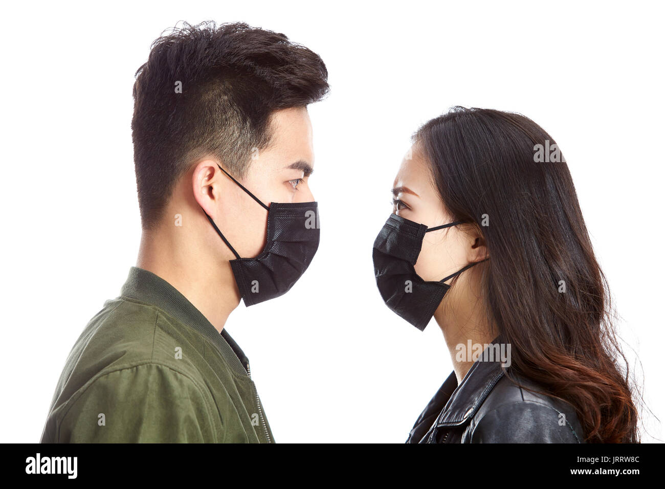 Giovani asiatici l uomo e la donna che indossa maschera nera fissando tra loro isolati su sfondo bianco. Foto Stock