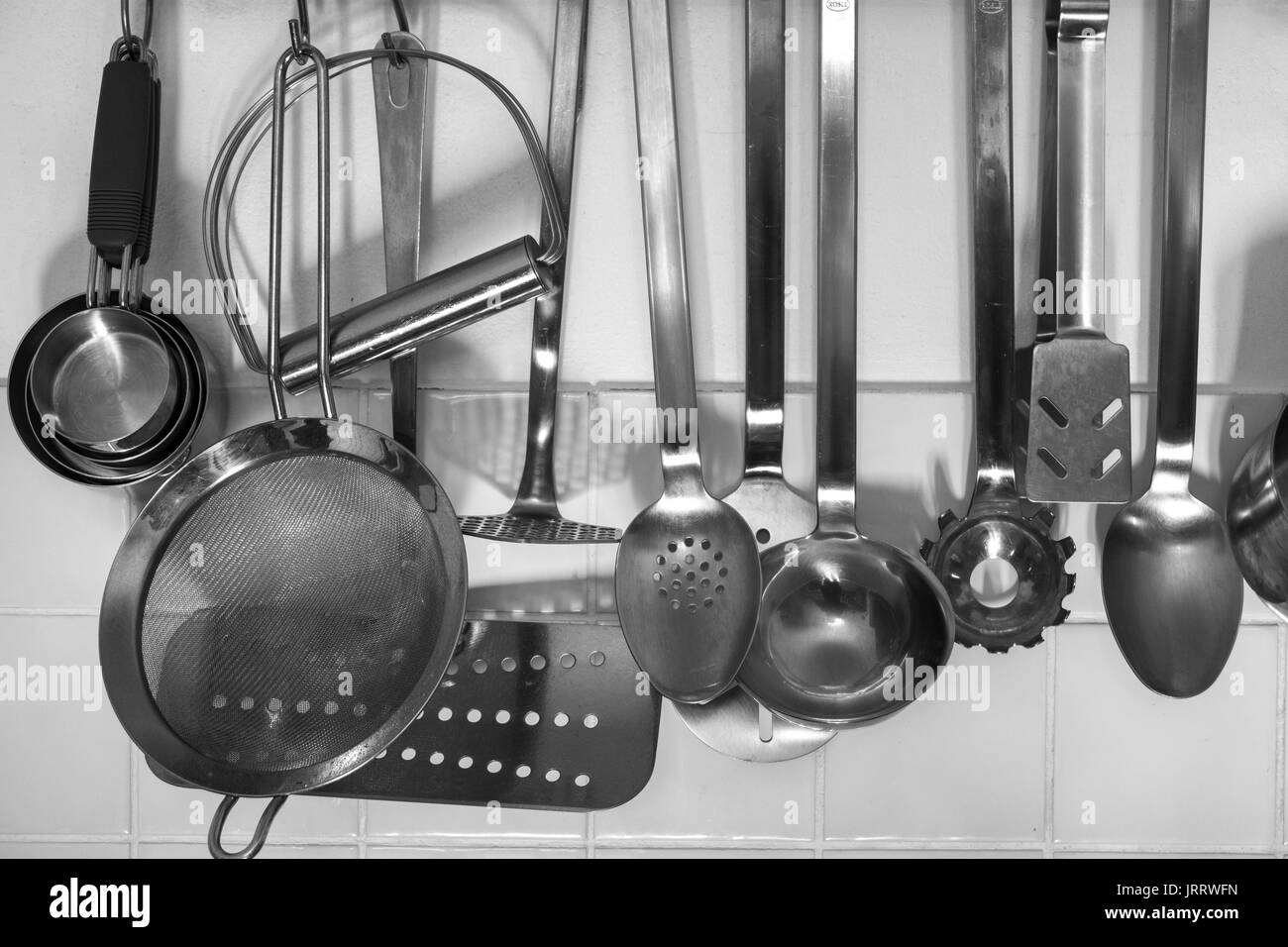 Vari utensili da cucina appesi da una rastrelliera Foto Stock