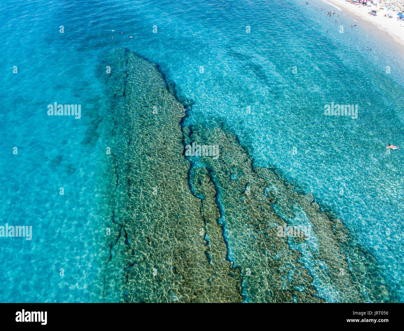 Vista aerea di rocce sul mare. Panoramica dei fondali marini visto dal di sopra, di acqua trasparente. Nuotatori, bagnanti galleggianti sull'acqua Foto Stock