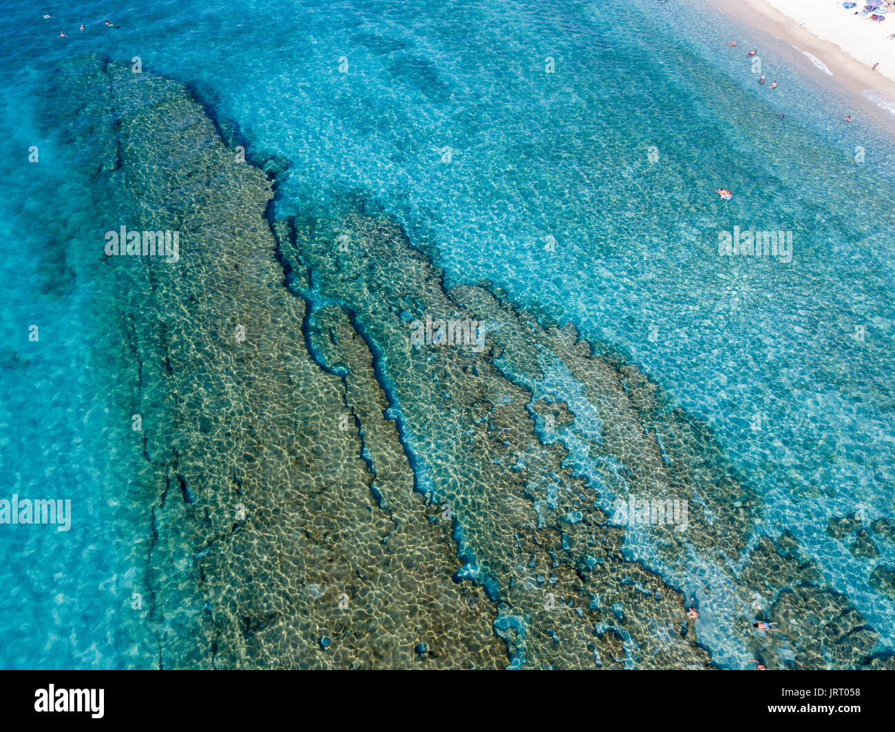 Vista aerea di rocce sul mare. Panoramica dei fondali marini visto dal di sopra, di acqua trasparente. Nuotatori, bagnanti galleggianti sull'acqua Foto Stock