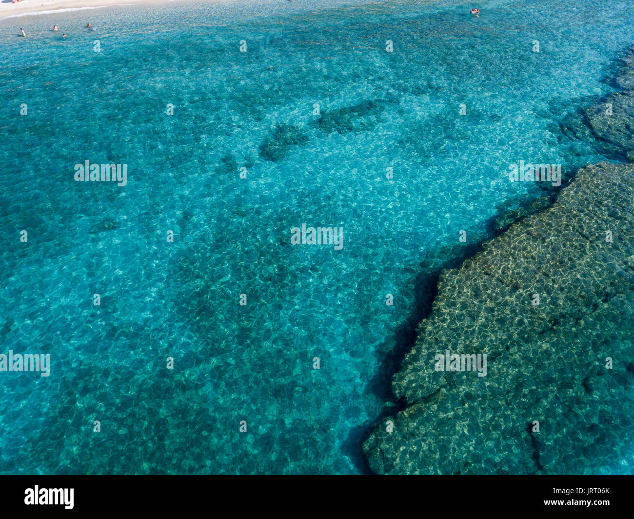 Vista aerea di rocce sul mare. Panoramica dei fondali marini visto dal di sopra, di acqua trasparente. Nuotatori, bagnanti galleggianti sull'acqua Foto Stock