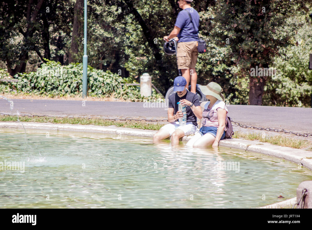 I turisti rinfrescarsi nelle calde giornate estive nella fontana di villa Borghese, Roma Italia Foto Stock