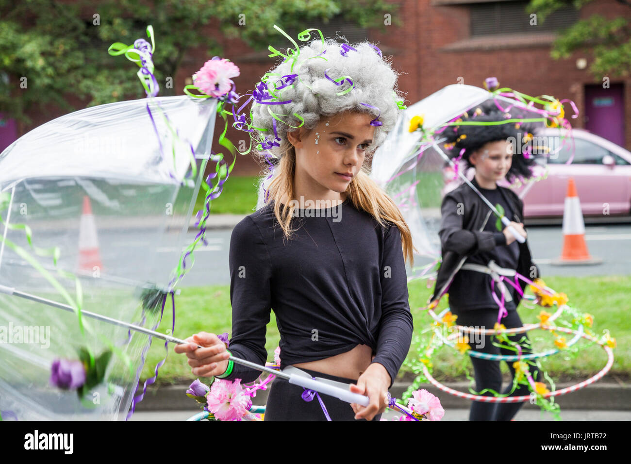 Didascalia 62/150 una ragazza giovane con ombrellone e fiori a Stockton International Riverside Festival parade Foto Stock