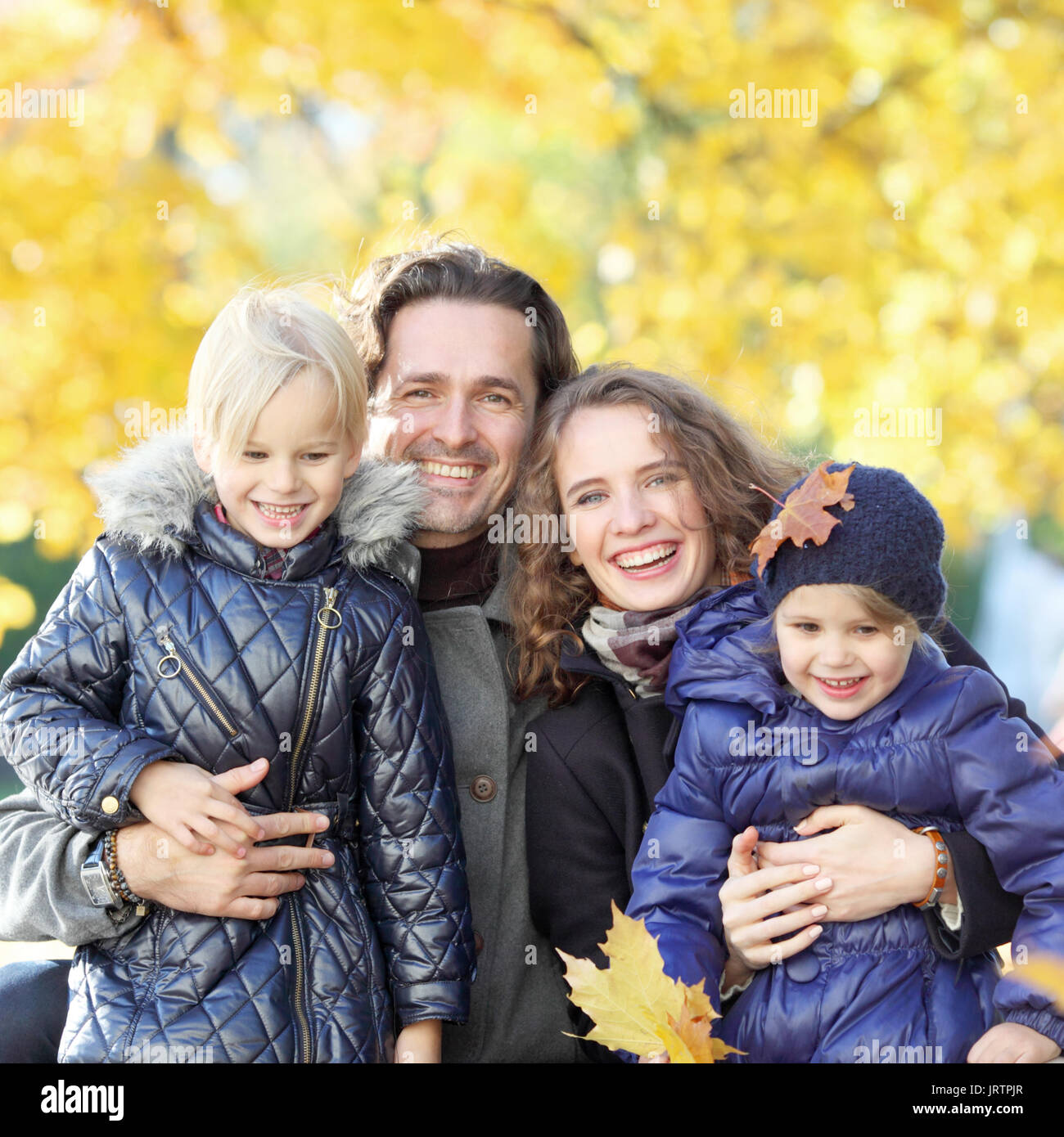 Ritratto di sorridenti famiglia con due bambini relax nel parco di autunno Foto Stock