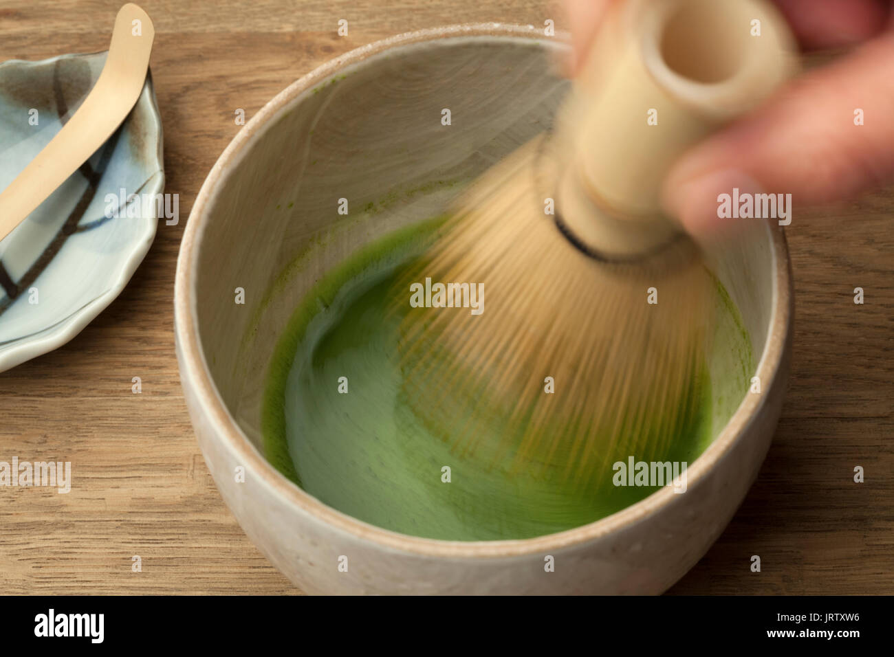 La preparazione di una tazza di tè matcha con una frusta di tè Foto Stock