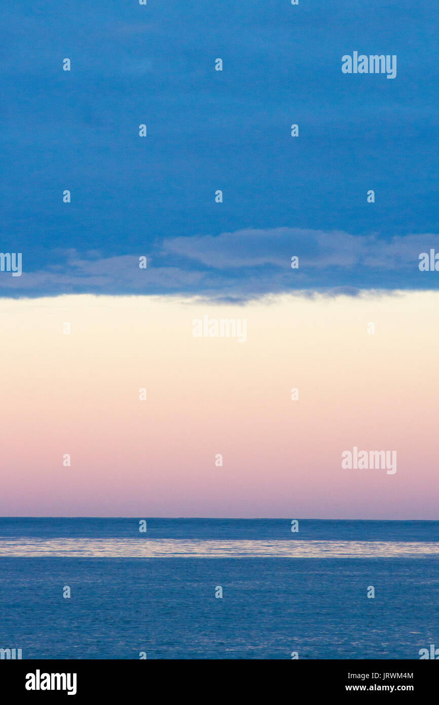 Oceano Atlantico subito dopo il tramonto con un cielo rosa e blu scuro nuvole sopra l'orizzonte Foto Stock