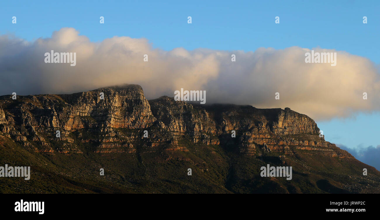 Forma delle nuvole sulla cima della montagna della tavola e i dodici apostoli come si vede al tramonto dalla spiaggia di Camps Bay a Cape Town, Western Cape, Sud Africa. Foto Stock
