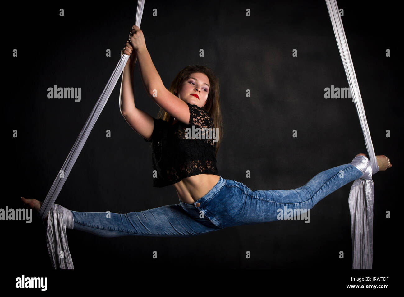 Trapezista donna facendo una certa flessibilità e robustezza trucchi su tessuti di seta Foto Stock