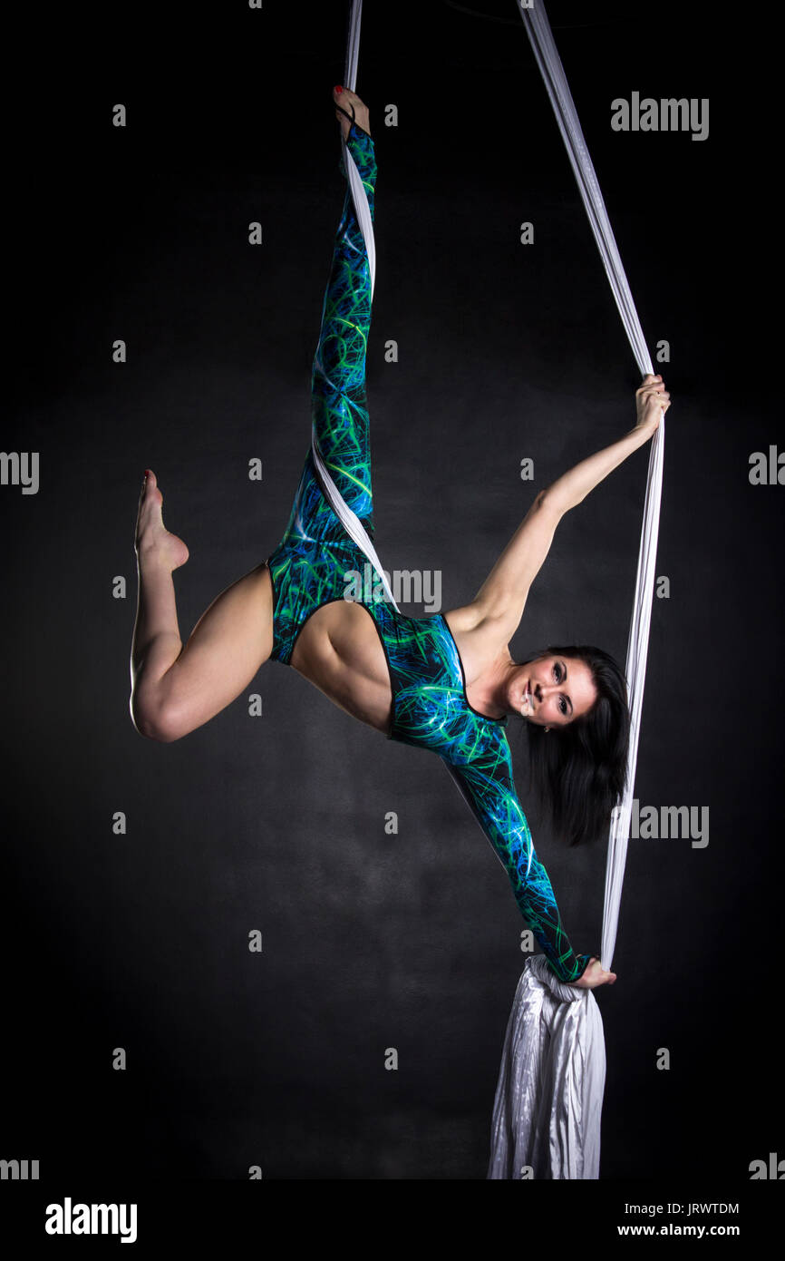 Trapezista donna facendo una certa flessibilità e robustezza trucchi su tessuti di seta Foto Stock