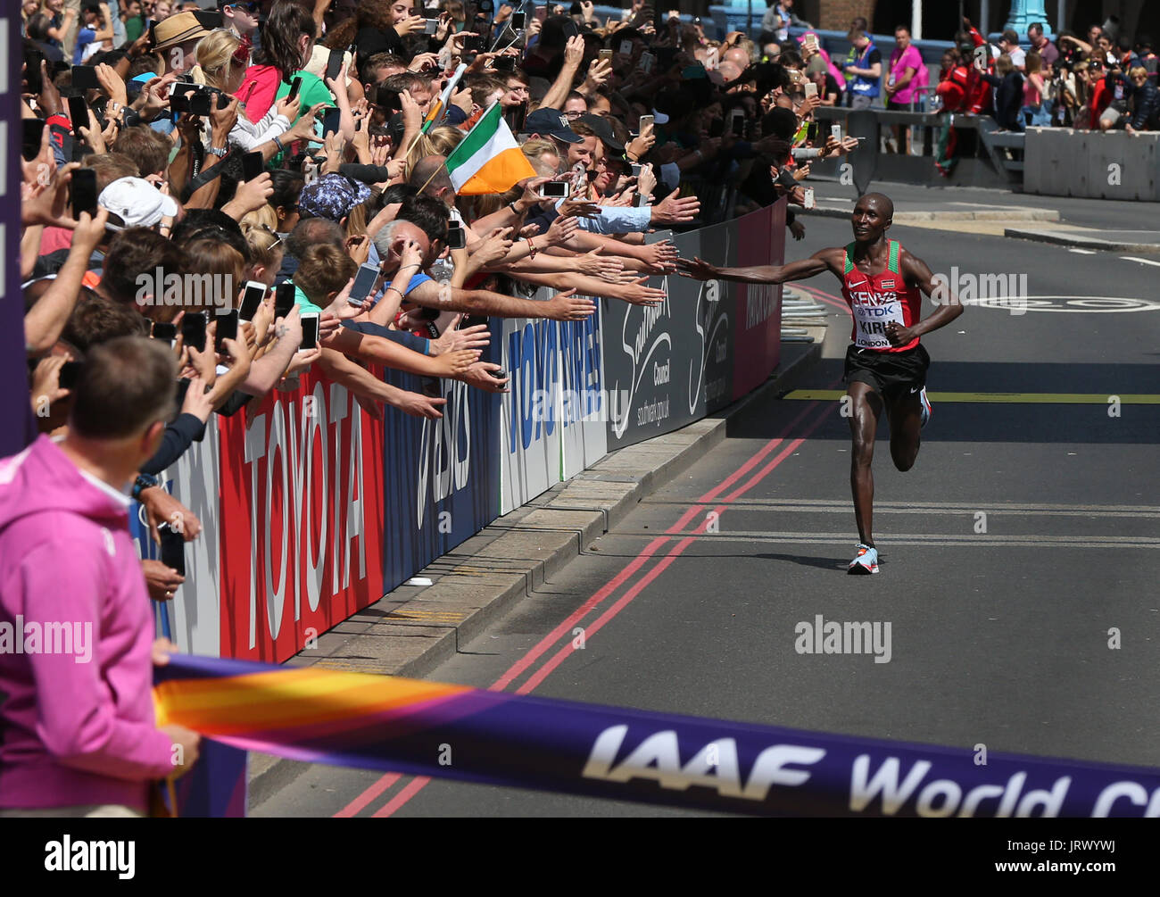 Il Kenya è Geoffrey Kirui Kipkorir alta cinque spettatori come lui si avvicina al traguardo in uomini maratona durante il giorno tre del 2017 IAAF Campionati del mondo presso il London Stadium. Foto Stock