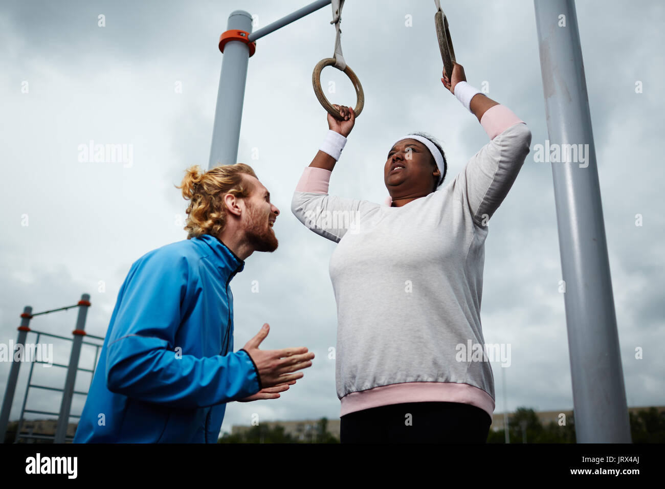 Esperti personal trainer motivare plus-size femmina di esercizio Foto Stock