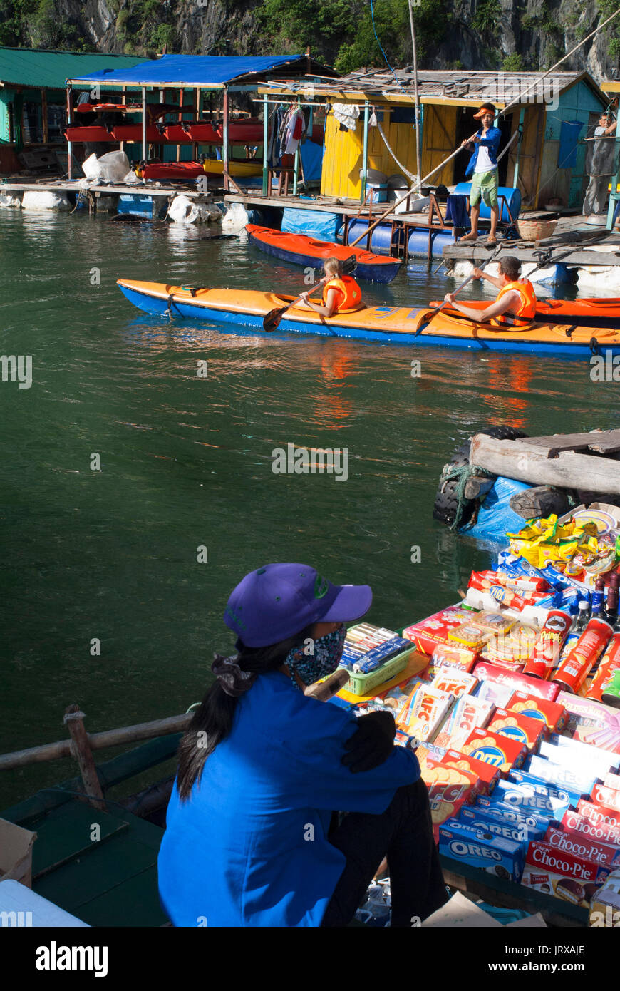 Donna remare una barca, la raccolta di rifiuti da imbarcazioni turistiche, Halong Bay, Viet Nam. remare una barca attraverso la baia di Halong, Vietnam. cat ba harbour Halong Bay Foto Stock