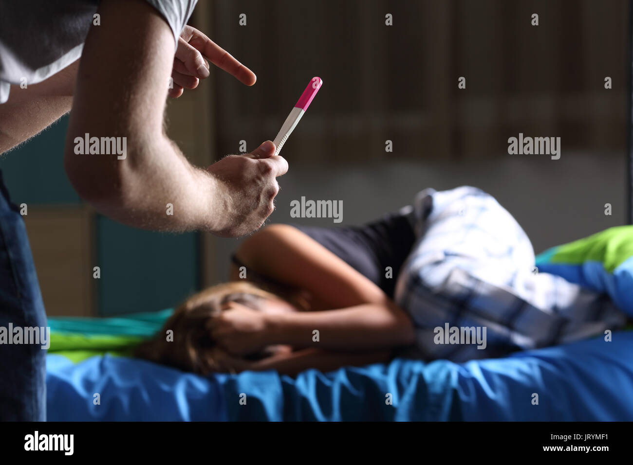 Padre chiedendo per la spiegazione che mostra test di gravidanza di una triste incinta teen chi piange sdraiato sul letto nella sua camera da letto Foto Stock