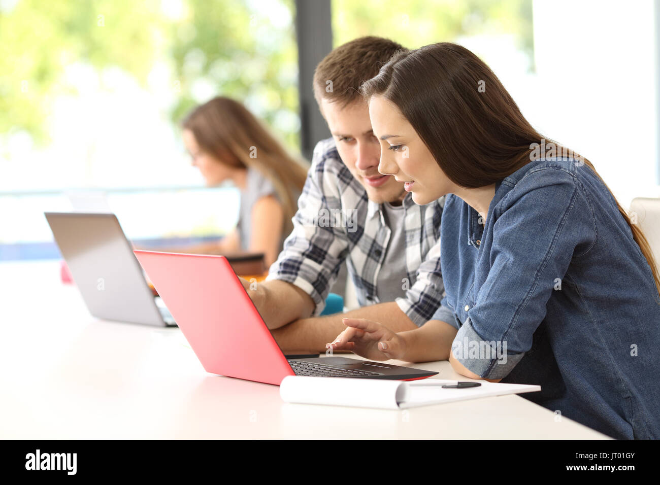 Due concentrati gli studenti lavorano insieme sulla linea con un laptop a una classe Foto Stock