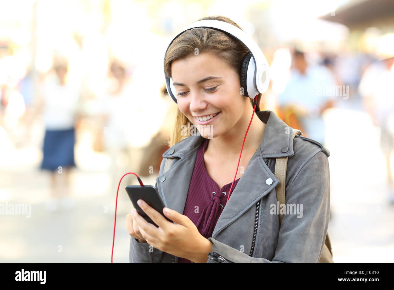 Felice adolescente ascoltando la musica che indossano le cuffie sulla strada Foto Stock