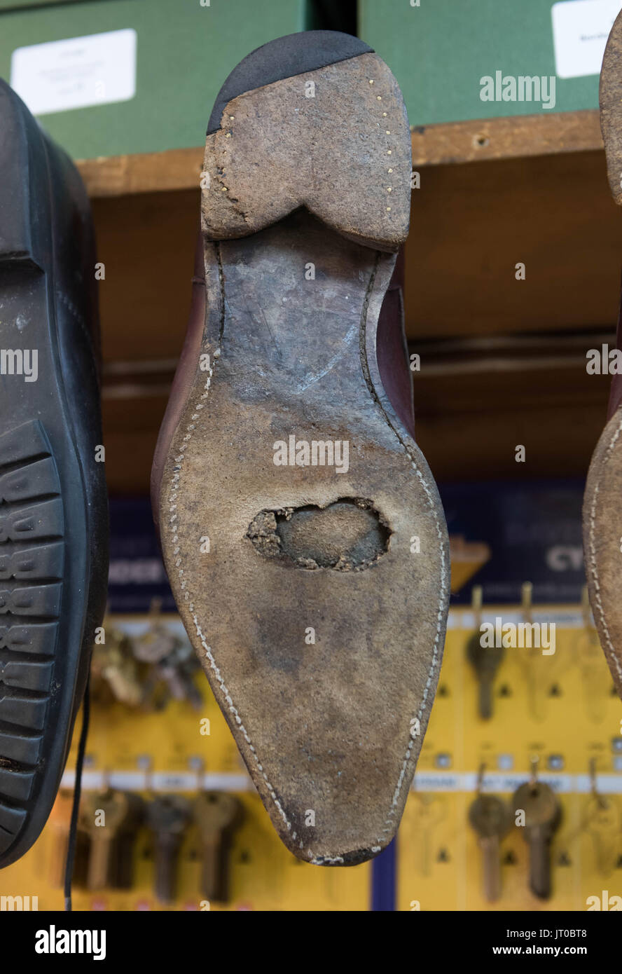 Foto ravvicinate degli attrezzi per la riparazione delle scarpe e delle calzature in un'officina tradizionale di ciabattine, mettendo in evidenza le suole, le attrezzature per la riparazione e il processo di risolina Foto Stock