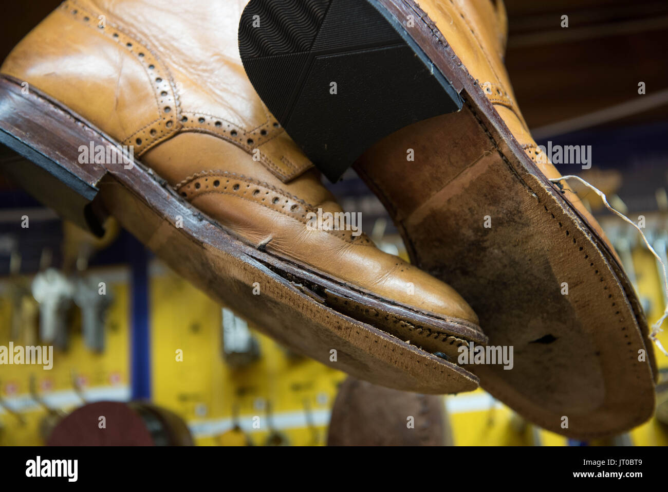 Foto ravvicinate degli attrezzi per la riparazione delle scarpe e delle calzature in un'officina tradizionale di ciabattine, mettendo in evidenza le suole, le attrezzature per la riparazione e il processo di risolina Foto Stock