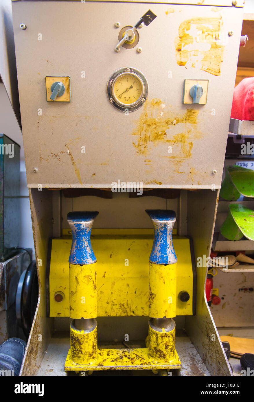 Foto ravvicinate degli attrezzi per la riparazione delle scarpe e delle calzature in un'officina tradizionale di ciabattine, mettendo in evidenza le suole, le attrezzature per la riparazione e il processo di risolina Foto Stock