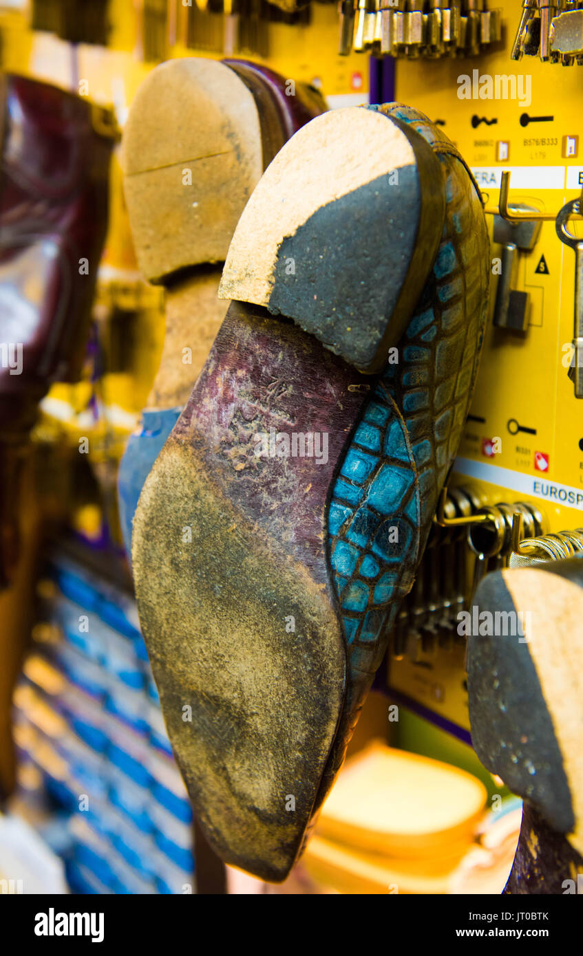 Foto ravvicinate degli attrezzi per la riparazione delle scarpe e delle calzature in un'officina tradizionale di ciabattine, mettendo in evidenza le suole, le attrezzature per la riparazione e il processo di risolina Foto Stock