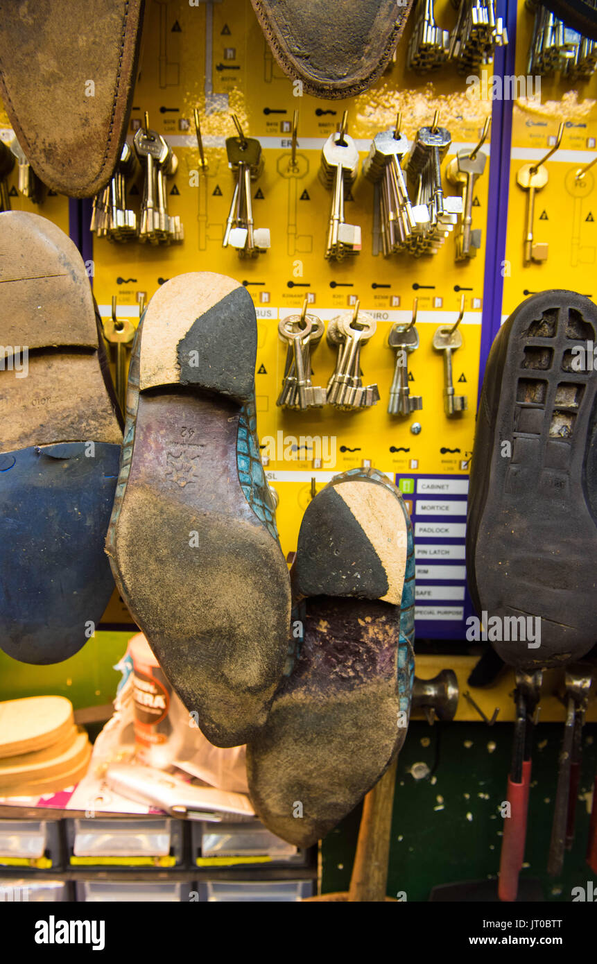 Foto ravvicinate degli attrezzi per la riparazione delle scarpe e delle calzature in un'officina tradizionale di ciabattine, mettendo in evidenza le suole, le attrezzature per la riparazione e il processo di risolina Foto Stock