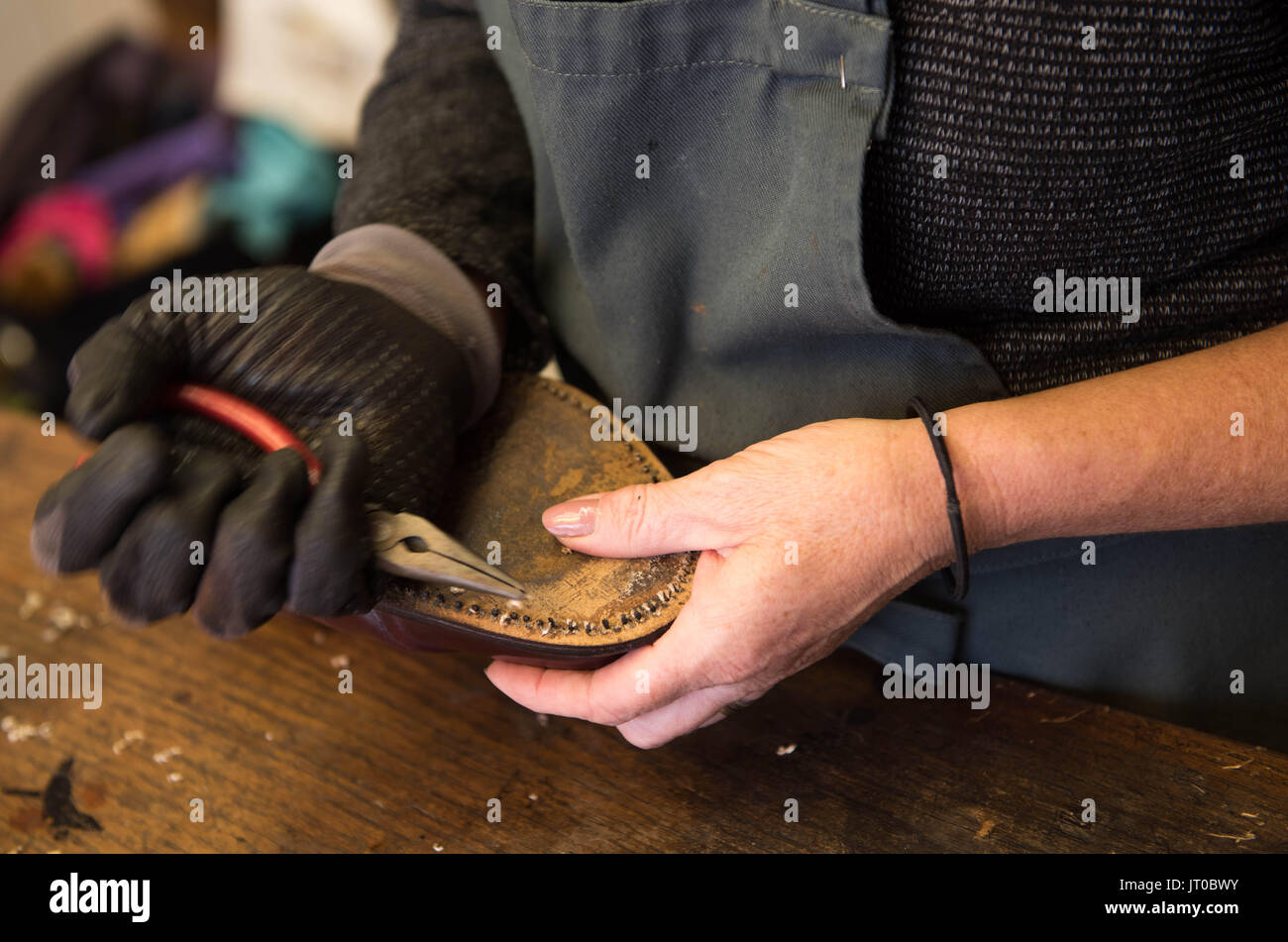 Foto ravvicinate degli attrezzi per la riparazione delle scarpe e delle calzature in un'officina tradizionale di ciabattine, mettendo in evidenza le suole, le attrezzature per la riparazione e il processo di risolina Foto Stock