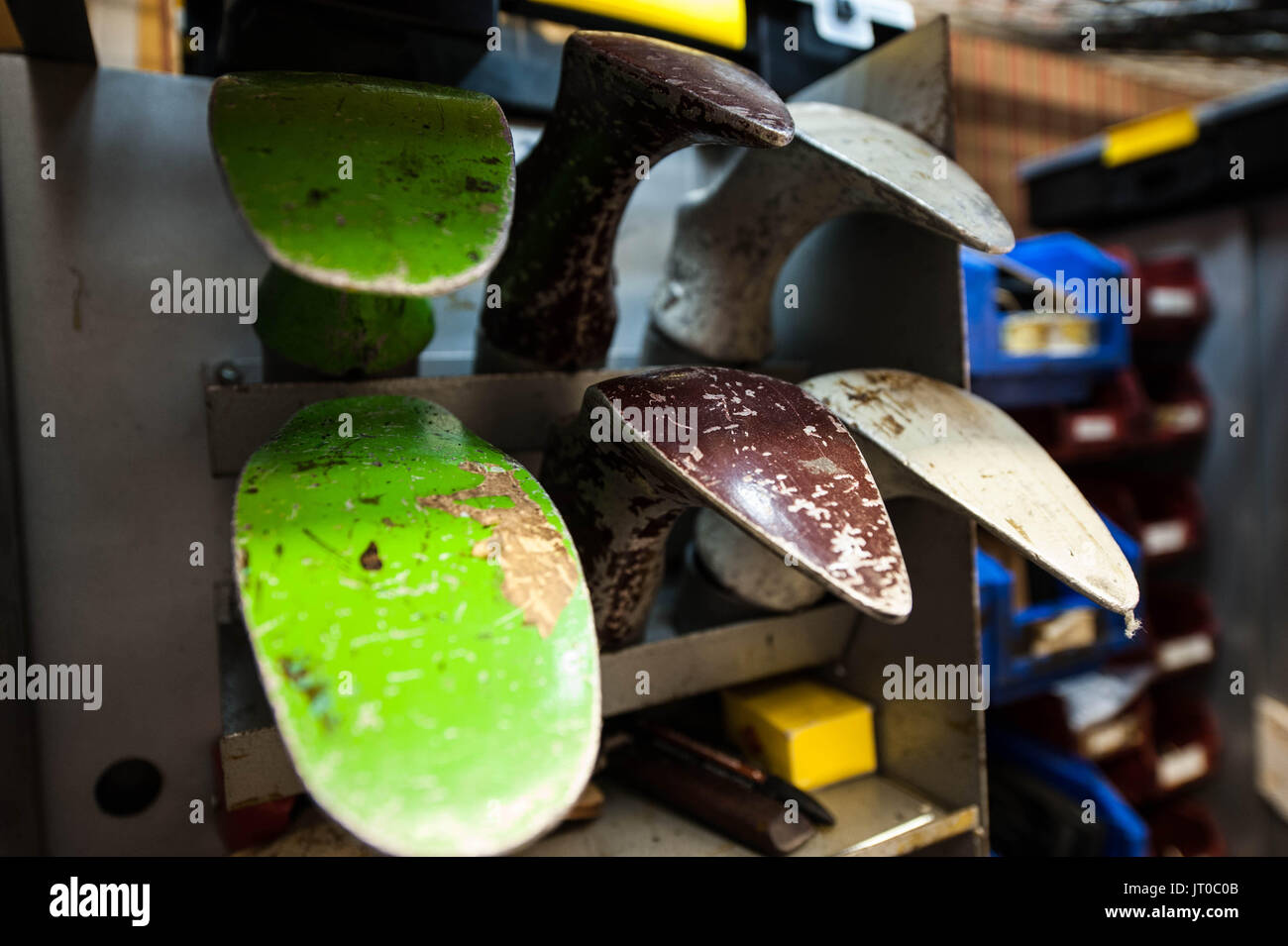 Foto ravvicinate degli attrezzi per la riparazione delle scarpe e delle calzature in un'officina tradizionale di ciabattine, mettendo in evidenza le suole, le attrezzature per la riparazione e il processo di risolina Foto Stock
