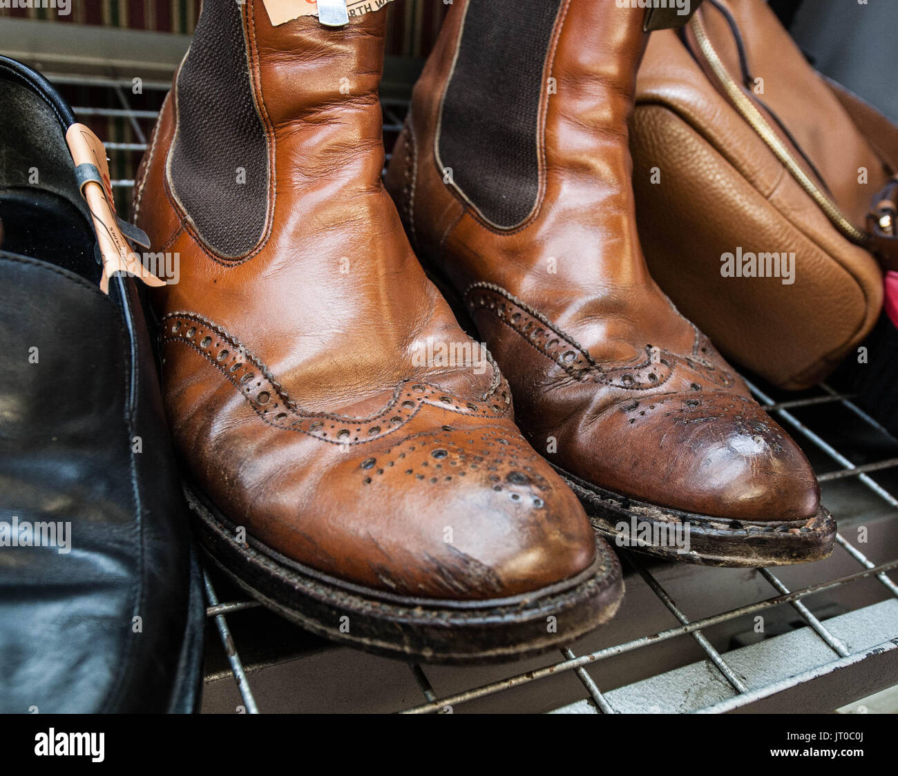 Foto ravvicinate degli attrezzi per la riparazione delle scarpe e delle calzature in un'officina tradizionale di ciabattine, mettendo in evidenza le suole, le attrezzature per la riparazione e il processo di risolina Foto Stock