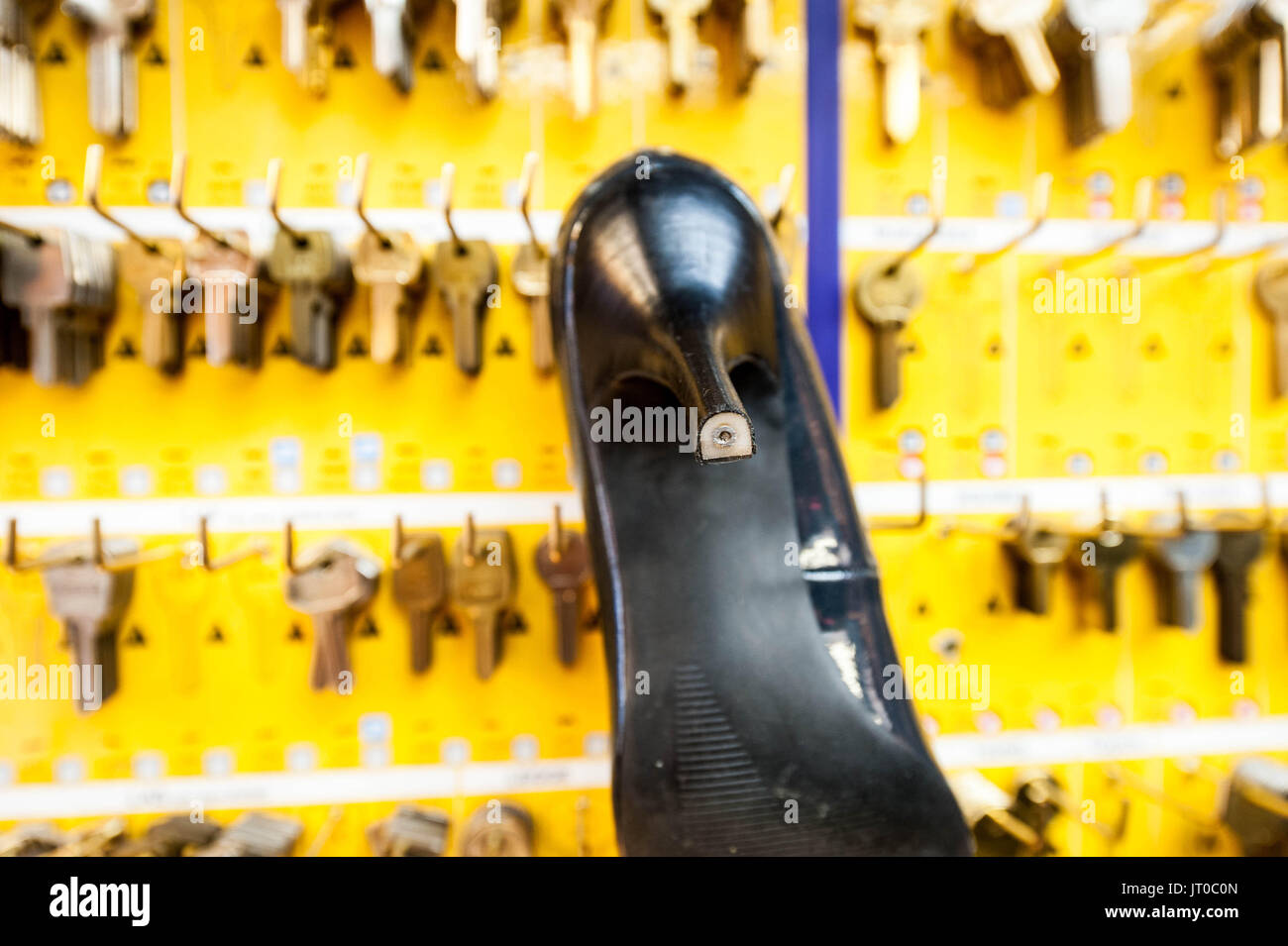 Foto ravvicinate degli attrezzi per la riparazione delle scarpe e delle calzature in un'officina tradizionale di ciabattine, mettendo in evidenza le suole, le attrezzature per la riparazione e il processo di risolina Foto Stock