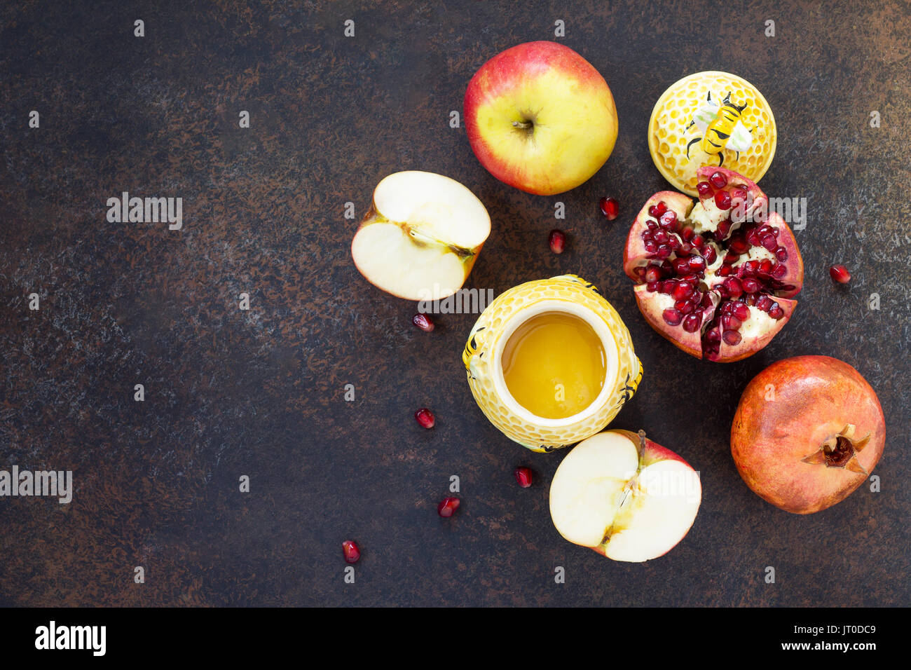 Il concetto di Rosh hashanah (ebreo Nuovo anno). Vacanze tradizionali simboli - miele, apple e melograno su una pietra o ardesia sfondo. Piatto, laici t Foto Stock