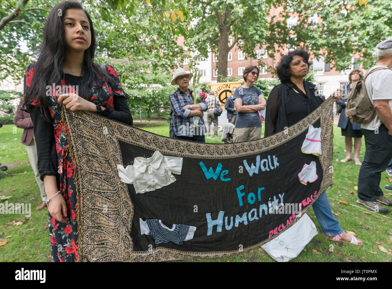 Londra, Regno Unito. Il 6 agosto, 2017. Londra, Regno Unito. Il 6 agosto 2017. Le donne in attesa di un banner "dobbiamo camminare per l'umanità" al London CND cerimonia in memoria delle vittime del passato e del presente sul 72º anniversario della caduta della bomba atomica su Hiroshima e la seconda bomba atomica è sceso su Nagasaki tre giorni più tardi. Dopo un certo numero di interventi e di prestazioni vi era un minuto di silenzio durante il quale il vice sindaco di Camden e altri di cui fiori intorno a commemorative ciliegio. Peter Marshall credito ImagesLive: Peter Marshall / ImagesLive/ZUMA filo/Alamy Live News Foto Stock