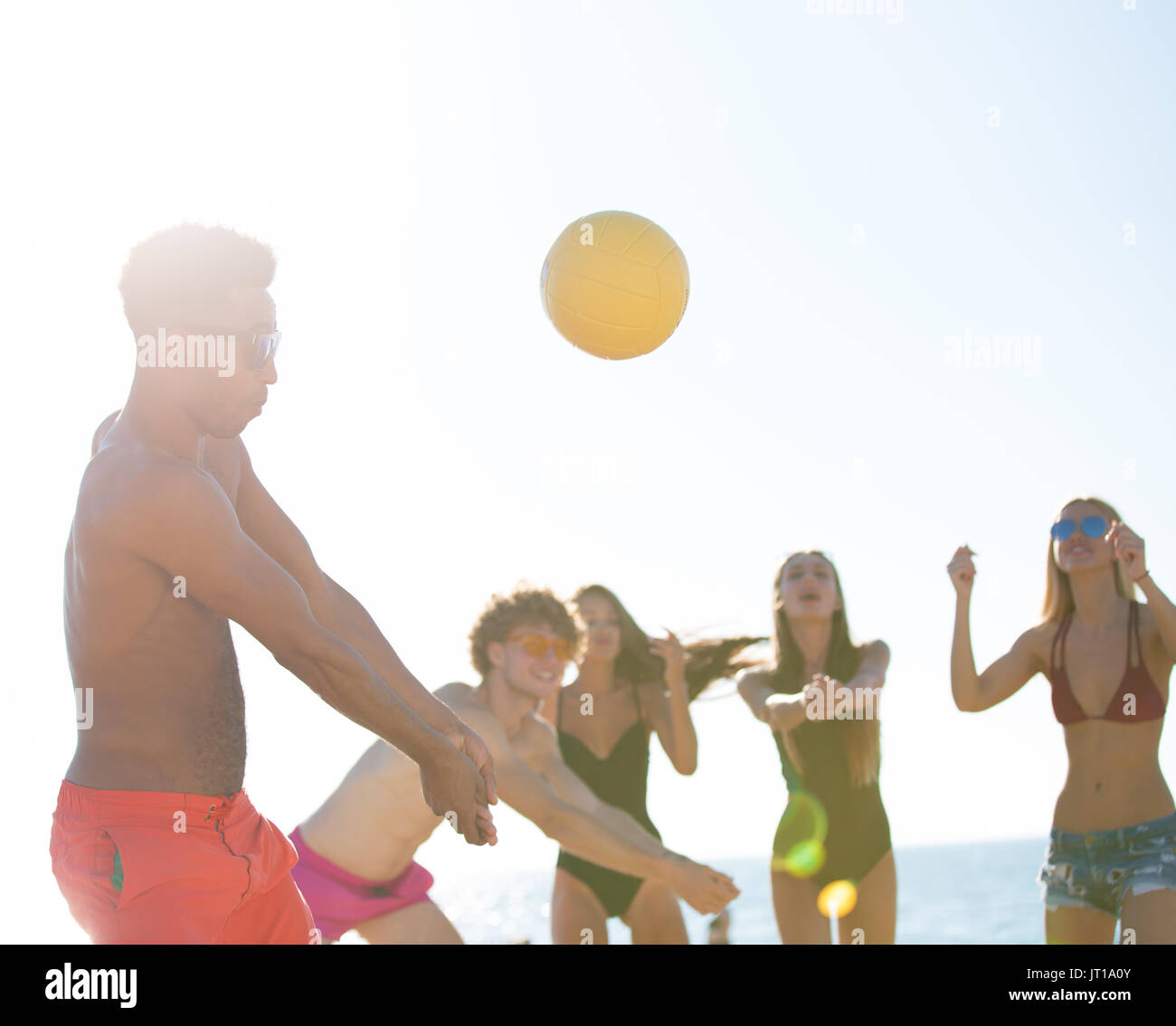 Gruppo di amici a giocare a beach volley in spiaggia Foto Stock