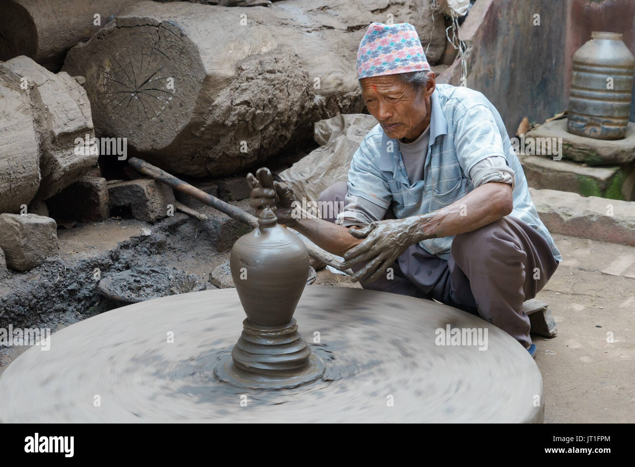 Potter funzionamento manuale di una mola di pietra in ceramica quadrata, Bhaktapur, Nepal. Foto Stock