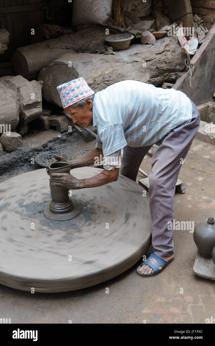 Potter funzionamento manuale di una mola di pietra in ceramica quadrata, Bhaktapur, Nepal. Foto Stock