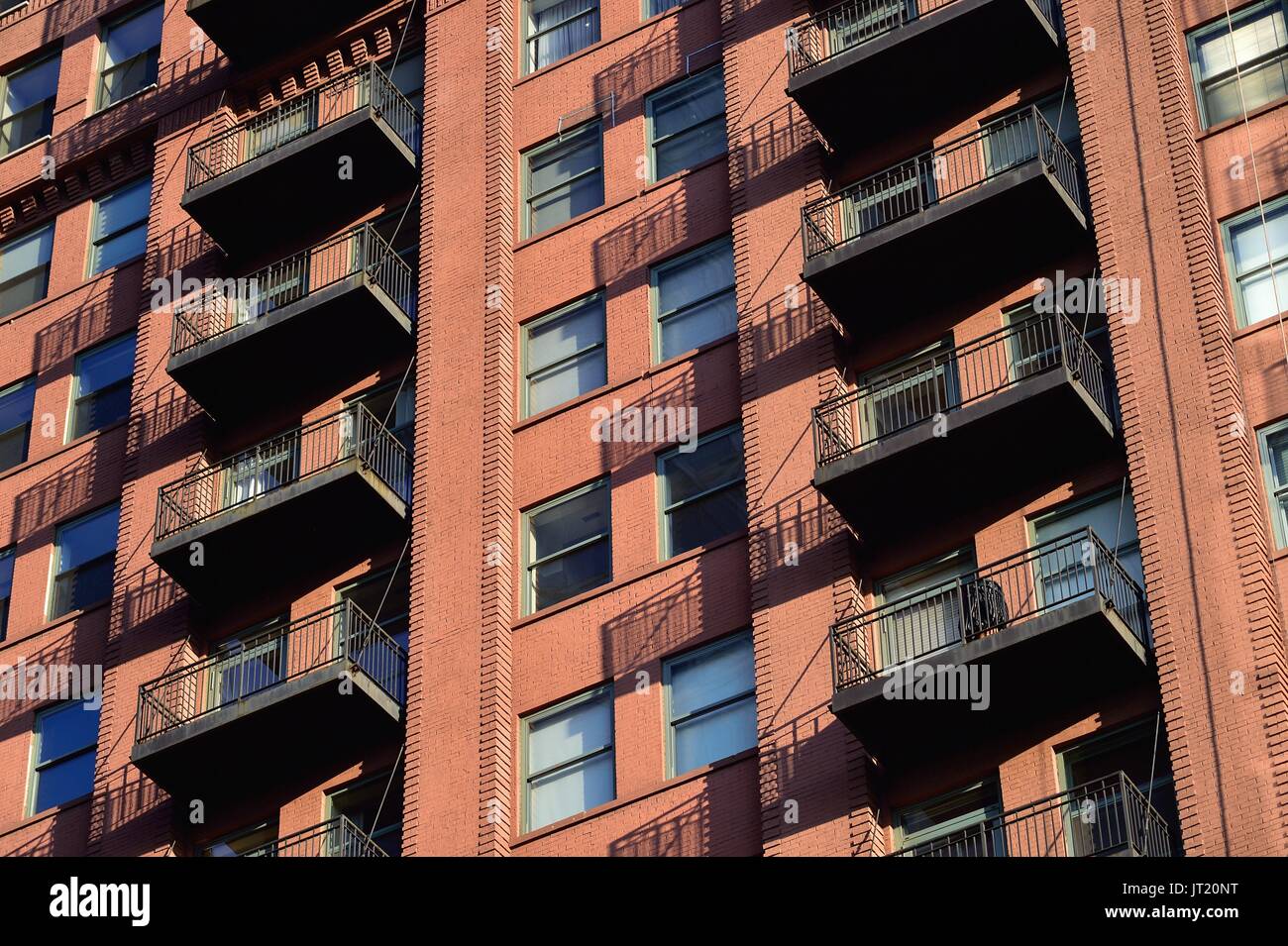 Chicago, Illinois, Stati Uniti d'America. La singola unità balconi gettano ombre sui mattoni adiacenti su un convertito commercail edificio in una struttura residenziale. Foto Stock