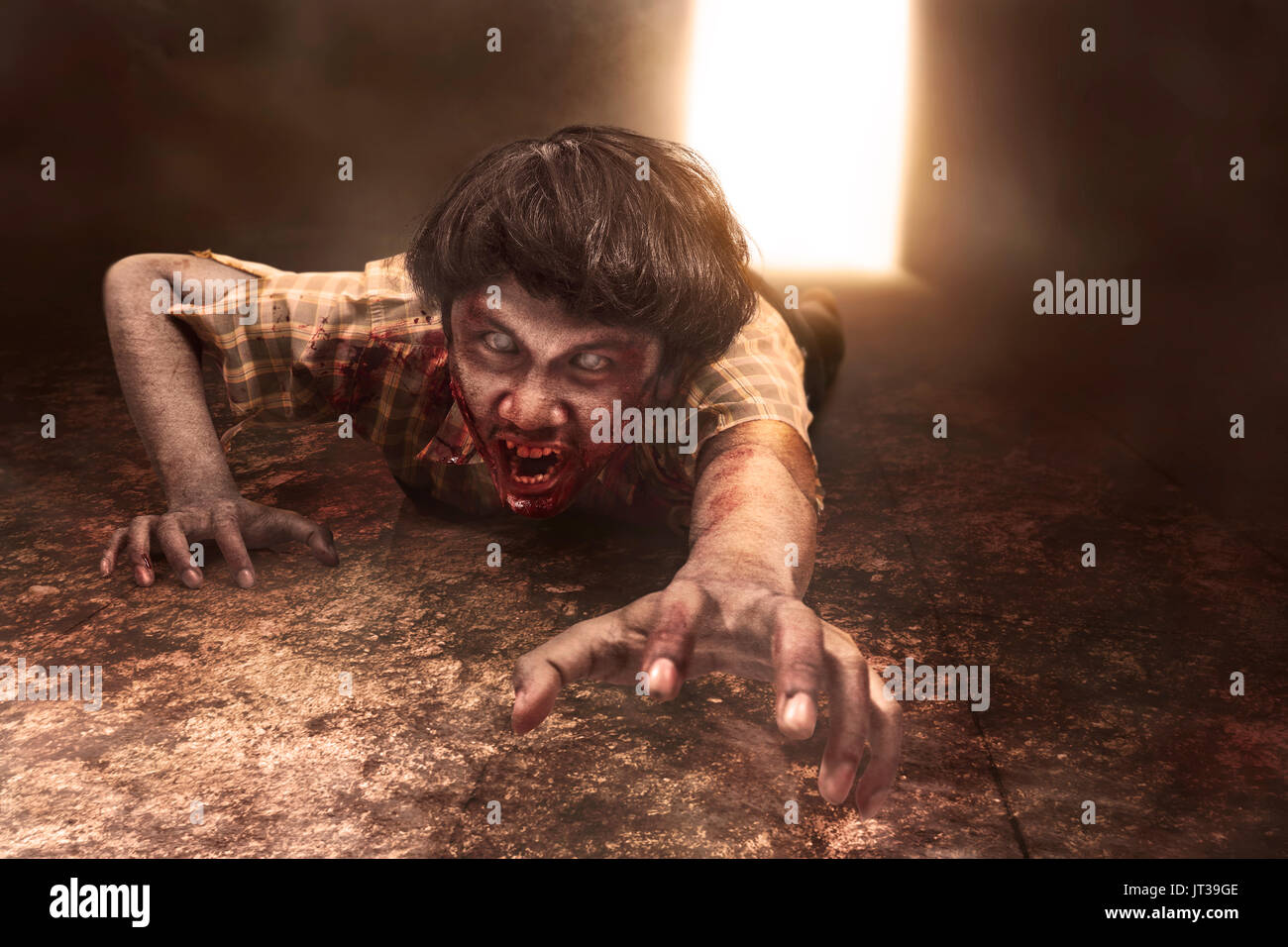 Scary asian zombie uomo è sdraiato sul pavimento in camera oscura Foto Stock