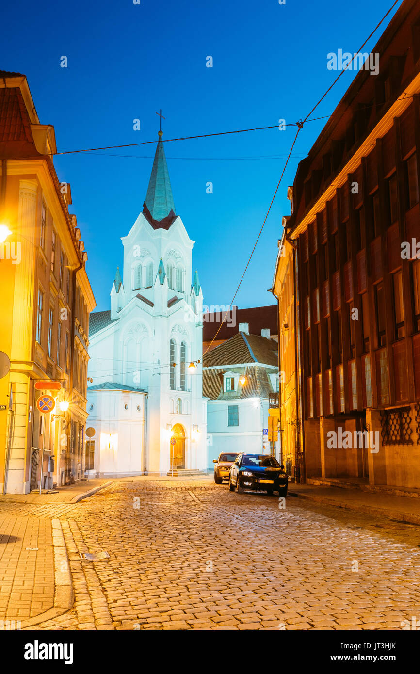 Riga, Lettonia. Torre bianca con cuspide piramidale di Nostra Signora dei Dolori o vergine di angoscia chiesa antica Chiesa cattolica sulla birra Pils Street In serata il Foto Stock