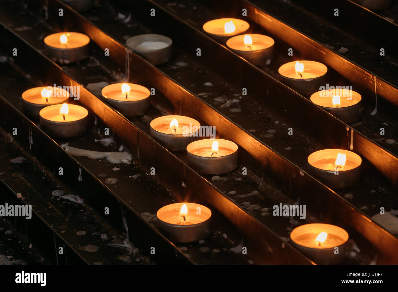 Gruppo di candele in chiesa. Candele a fiamma luminosa di notte. Foto Stock