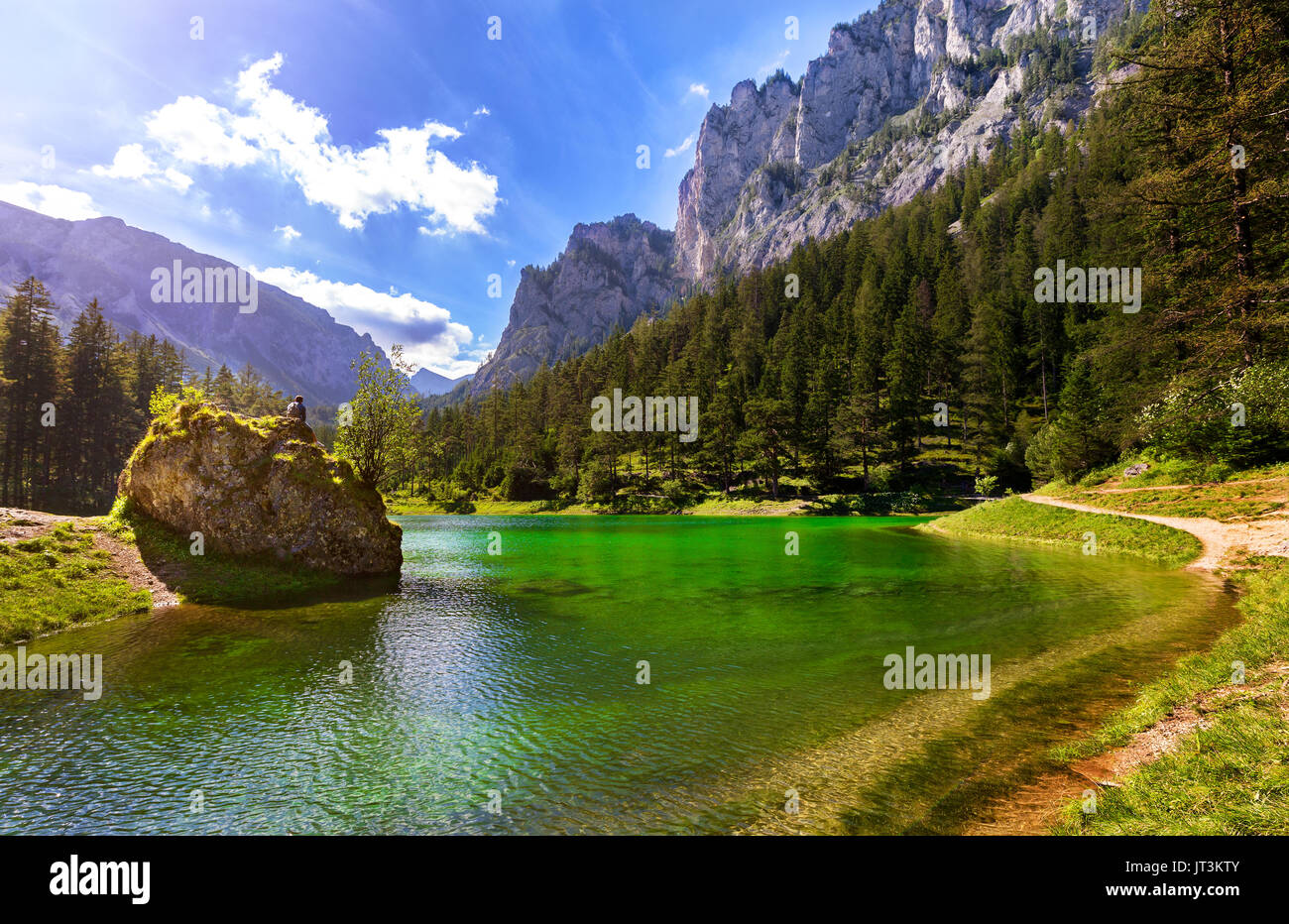 Uomo seduto sulla roccia e rilassarsi nella natura al verde del bellissimo lago Foto Stock