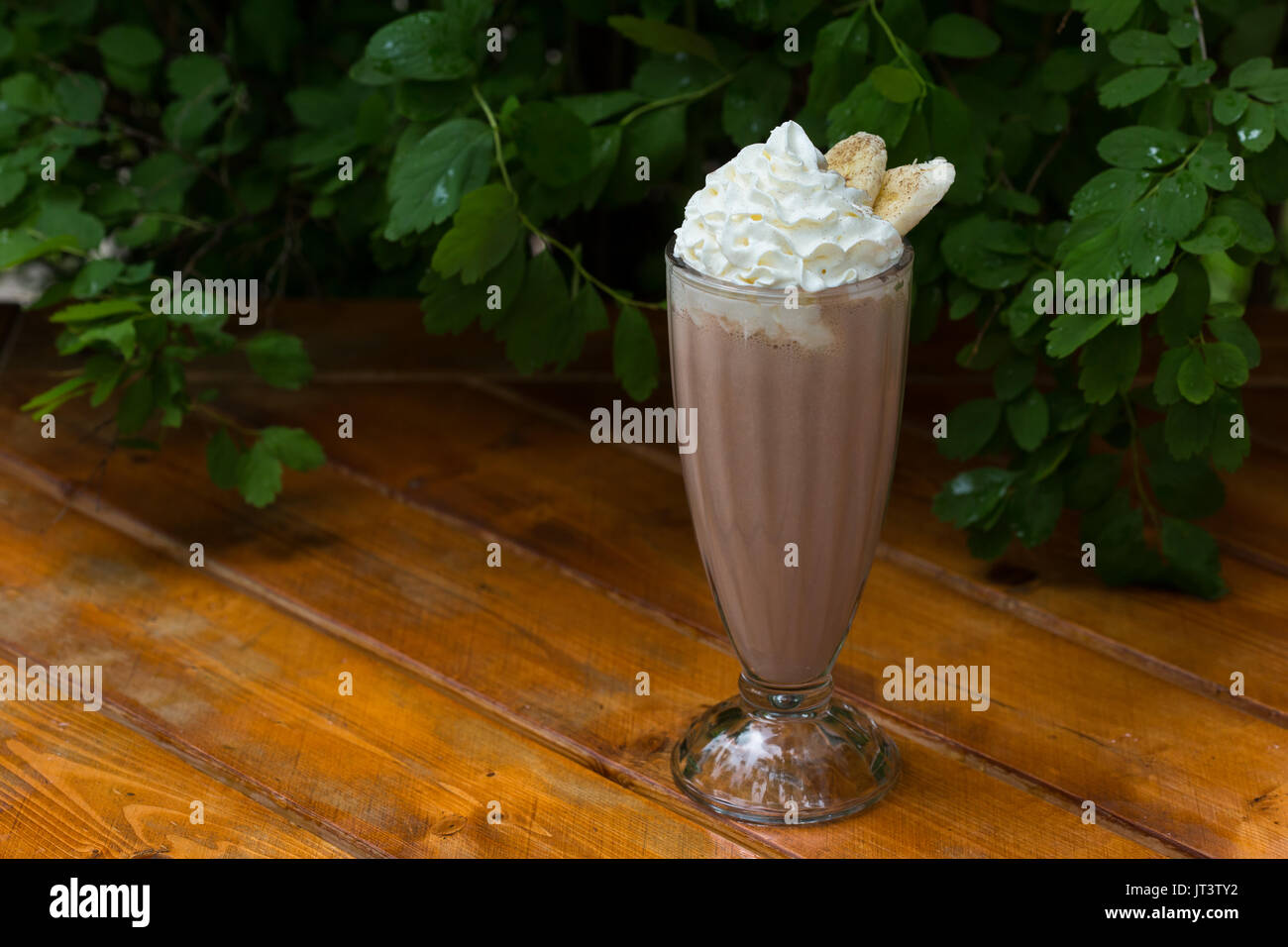 Frullato di banane in un bicchiere su un sfondo di legno. banana cocktail. spazio copia Foto Stock