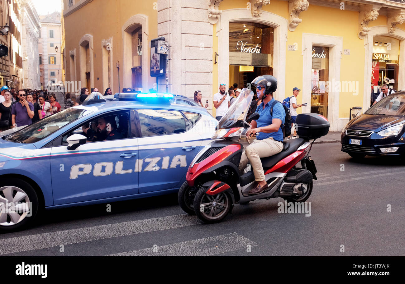 Roma Italia Luglio 2017 - Scooter rider superato da una polizia polizia auto con luce blu lampeggiante in strade di città fotografia scattata da Simon Dack Foto Stock