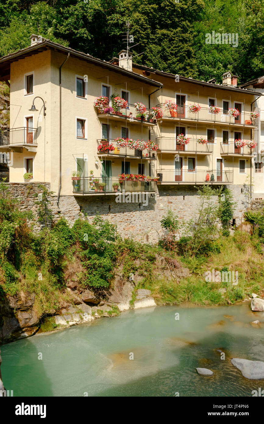 Pittoresche case con fiori blossonig su passerelle vicino al fiume Lys, girato in una luminosa giornata estiva a Fontainemore, valle del Lys, Aosta, Italia Foto Stock