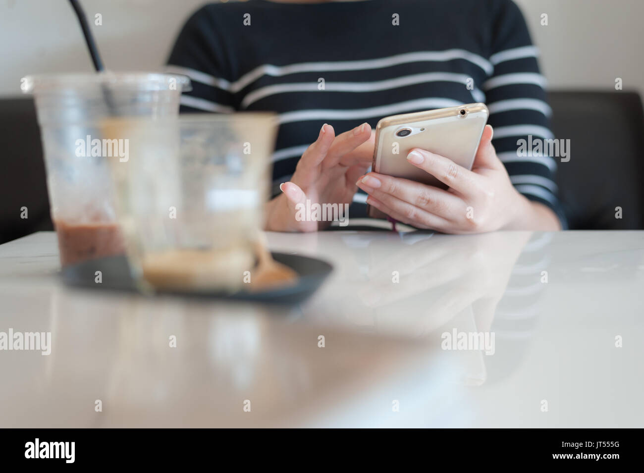 Donna che utilizza smartphone mentre si beve il caffè nella caffetteria sul weekend relax stile di vita con il mobile internet e il concetto di tecnologia Foto Stock