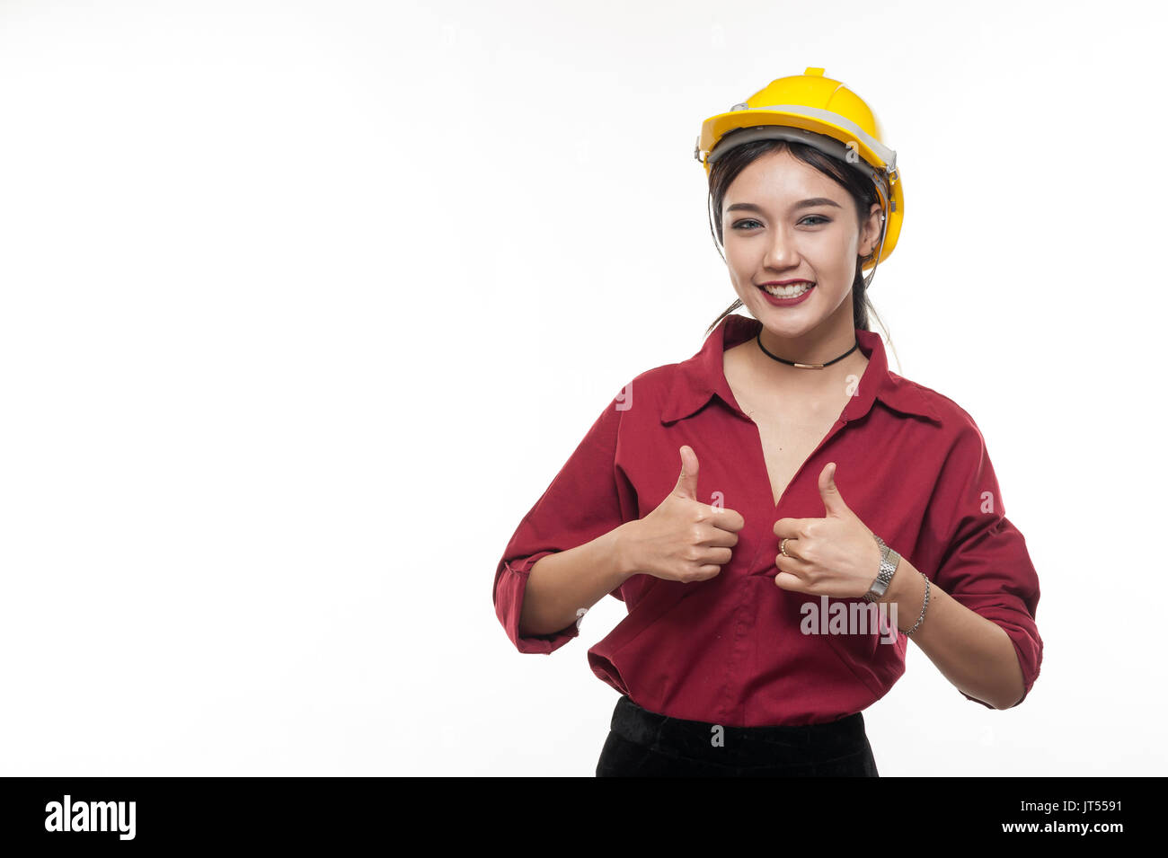 Donna asiatica ingegnere in maglietta rossa e gialla cappuccio di sicurezza mostra Thumbs up. persone gesticolando in business e concetto enginerring Foto Stock