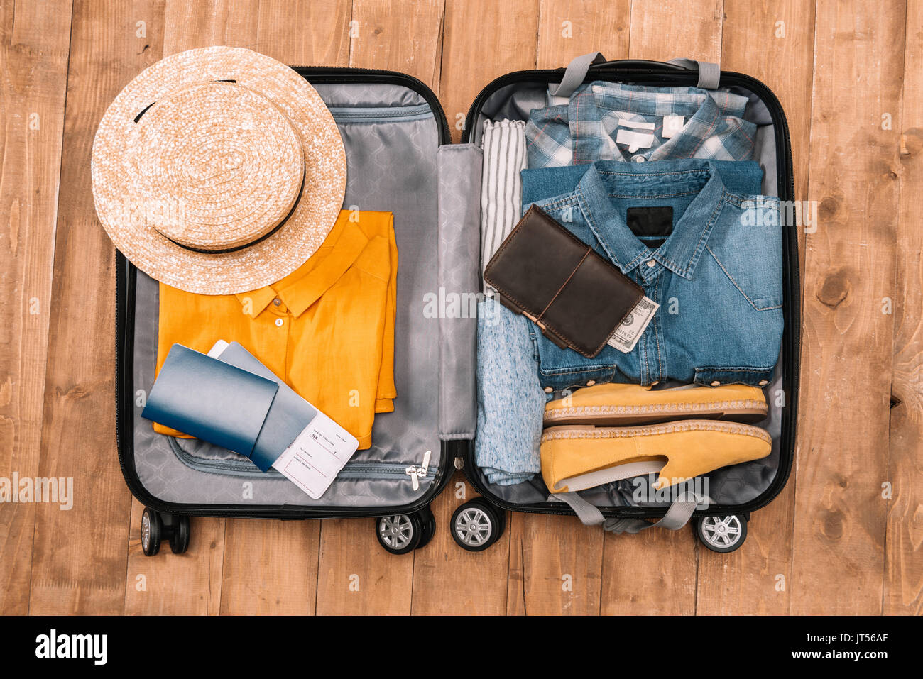 Pronto per il concetto di viaggio. Vista dall'alto di Essentials per turisti con abiti, accessori e gadget, portafogli, passaporto, smartphone nel sacchetto. Foto Stock