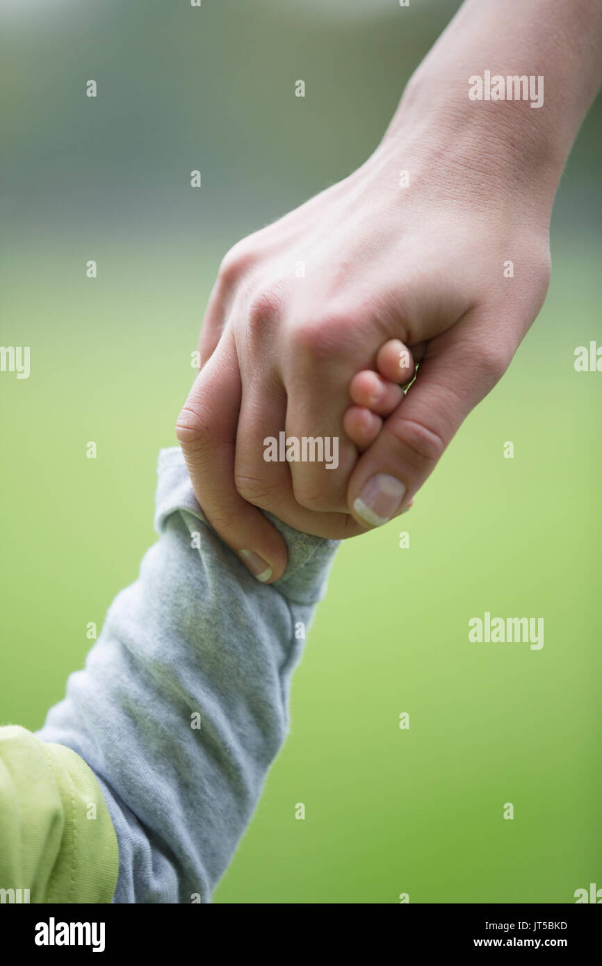Close up di madre e figlio tenendo le mani all'esterno. La paternità, amore e stare insieme concetto. Foto Stock Close up di madre e figlio tenendo le mani all'esterno. La paternità, amore e stare insieme concetto. Foto Stock